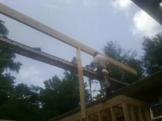 Carpenter setting a ridge beam over a new addition frame — Ice Dam Removal by Roofing Brothers in Cosmos