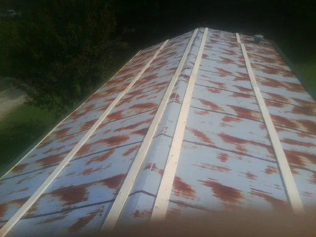 Rusted metal roof panels with new wood purlins before replacement — Storm Damage Roof Repair in Cosmos by Roofing Brothers