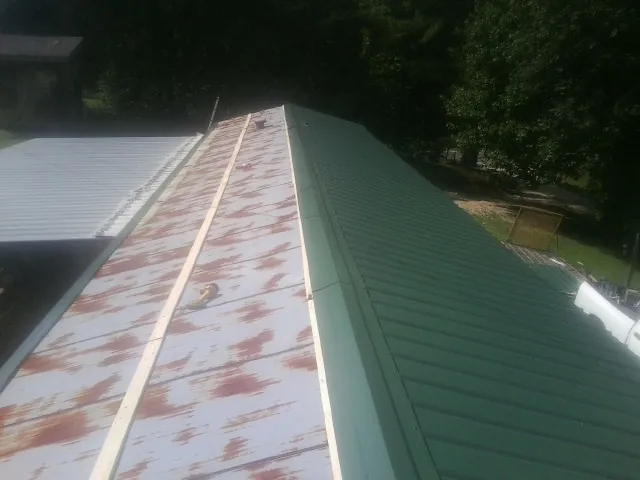 Old rusted panels beside newly installed green metal roofing — Wind Damage Roof Repair by Roofing Brothers in Cosmos