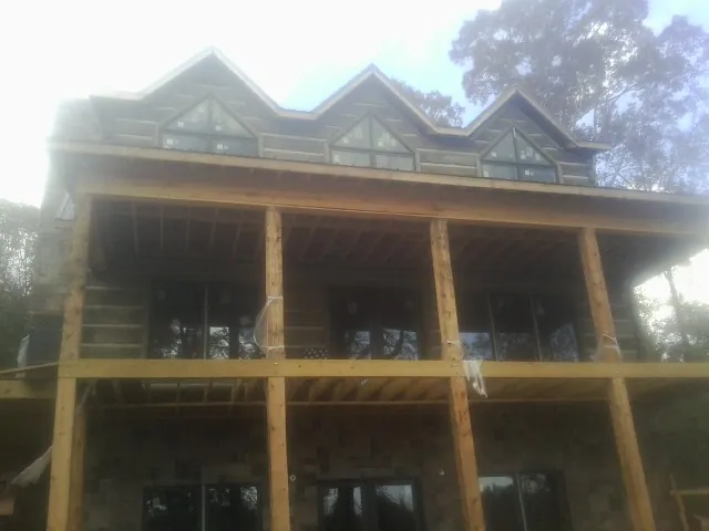 Dormers and porch framing on a large log home under construction — Roof Coating work by our crew in Cosmos