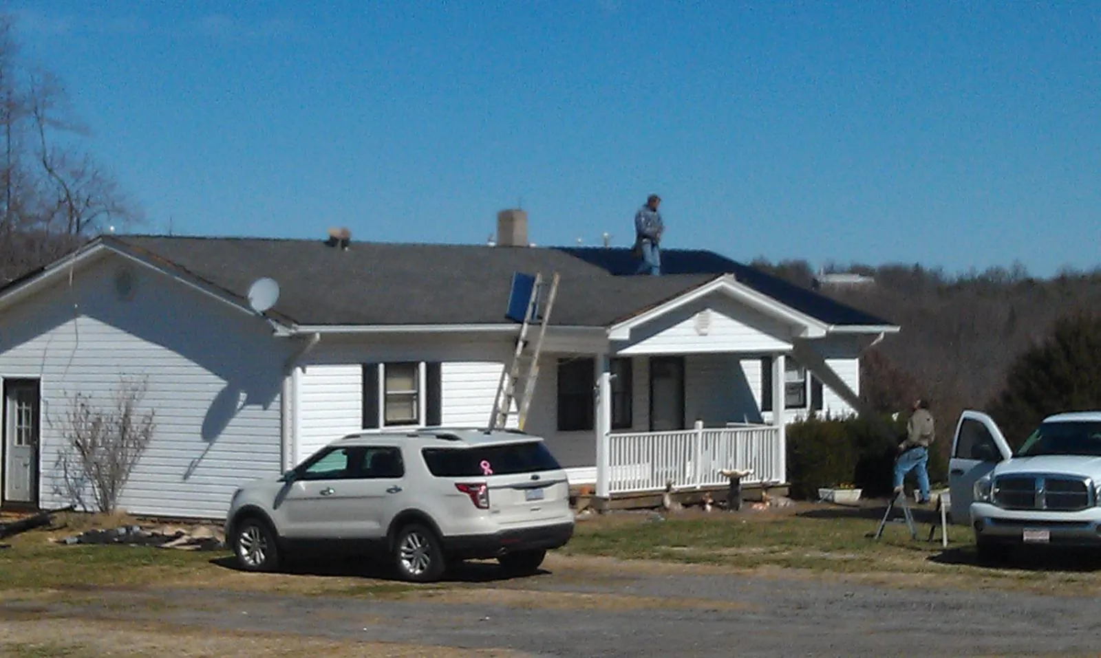 Roofers stripping shingles from a white ranch house roof in Cosmos