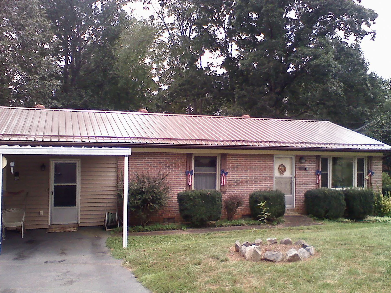 Bronze metal roof and carport on a brick ranch home — Roof Repair work by our crew in Cosmos
