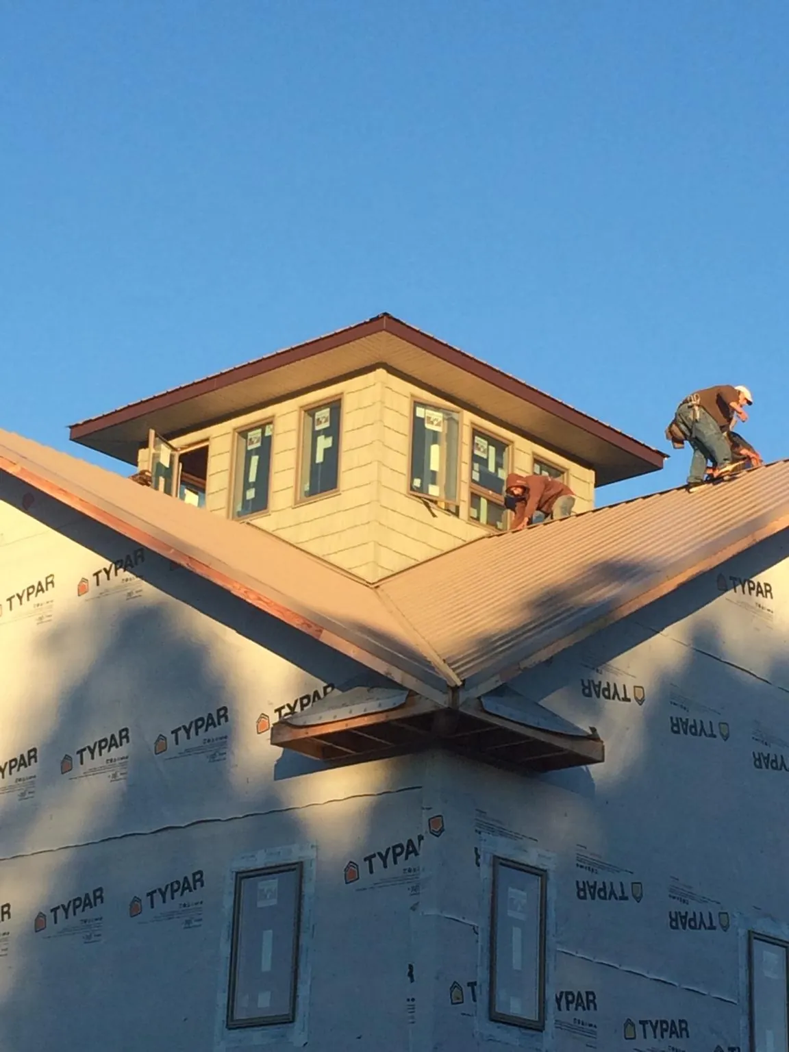 Roofers working around a rooftop cupola on a new metal roof at sunset — Roof Waterproofing in Cosmos by Roofing Brothers